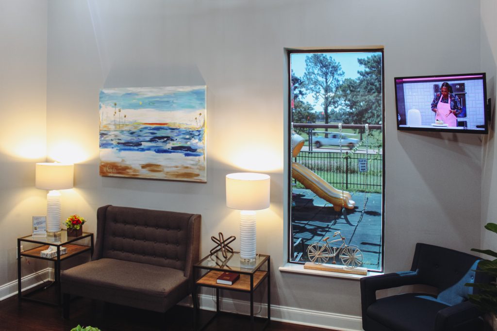 The waiting room with lamps, a sofa and a coastal painting