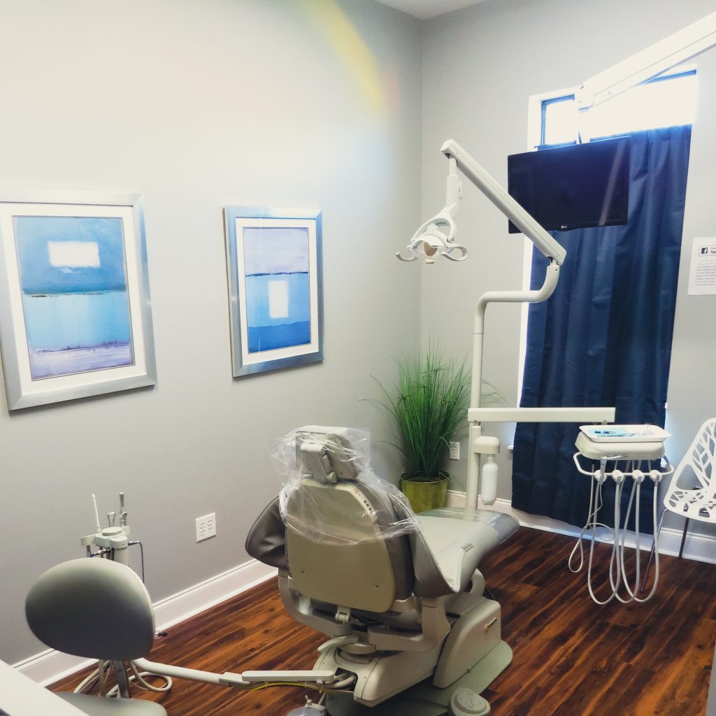 A treatment room with a dental chair and blue artwork