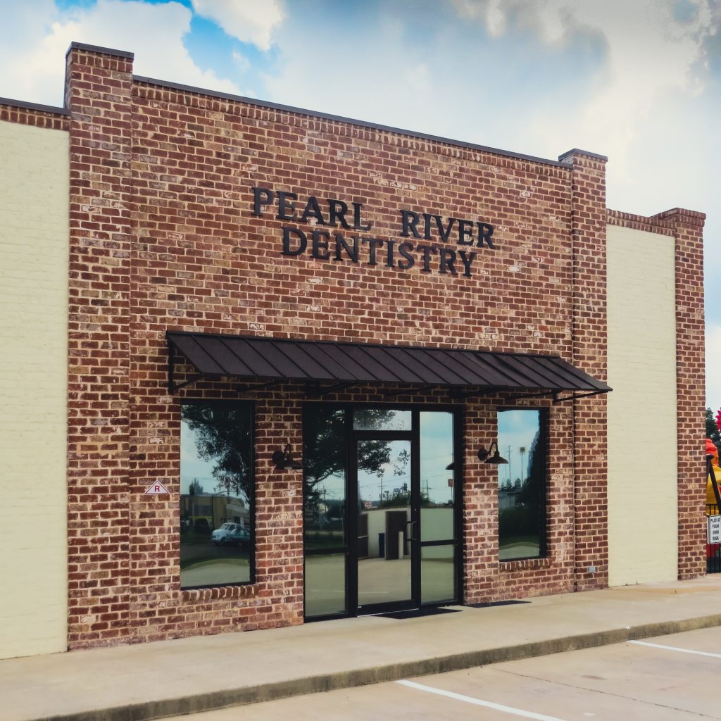 The red-brick Pearl River Dentistry building with a bronze awning over the front doors