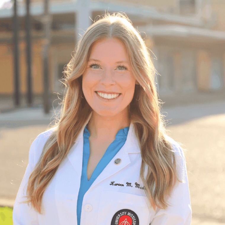 Dr. Karsen Maddox in a white coat, smiling outdoors